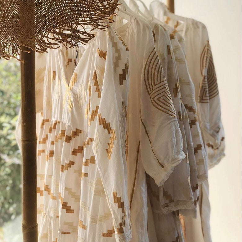 Light-colored clothing with geometric patterns hanging on a rack outdoors.