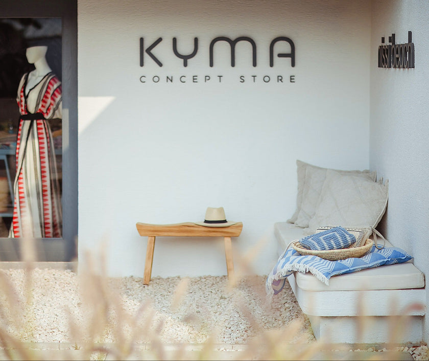 Kyma Concept Store interior with a chair, table, and mannequin.